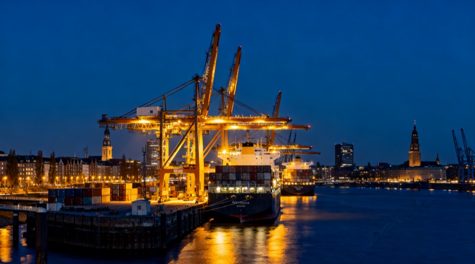 Nighttime panorama of Hamburg Port with illuminated cranes and ships.